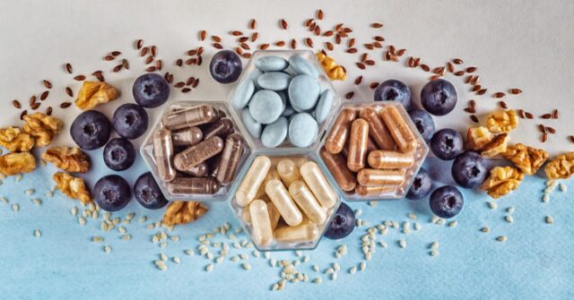 A mix of different dietary supplements and some fresh nuts, berries and seeds.