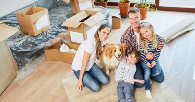 Family with a dog and packing boxes in lounge room of new home they just moved into.